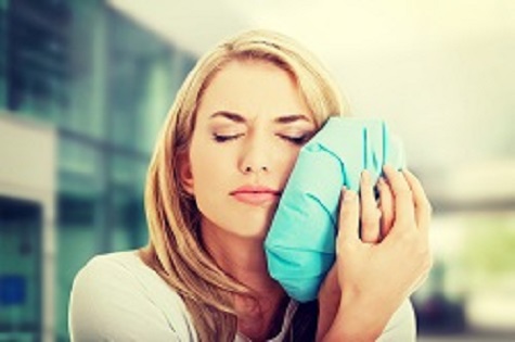 woman holding ice pack to face in pain, root canals Yakima, WA